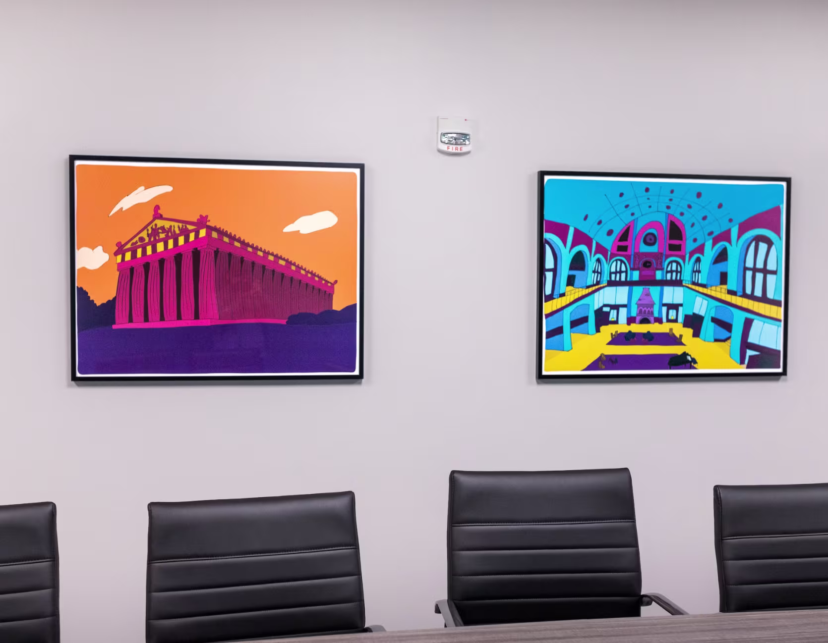 Two framed prints showing the Parthenon and Union Station in vibrant colors above conference table